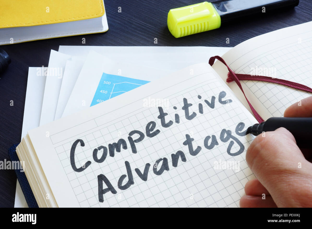 Man is writing words Competitive advantage in the notepad. Stock Photo