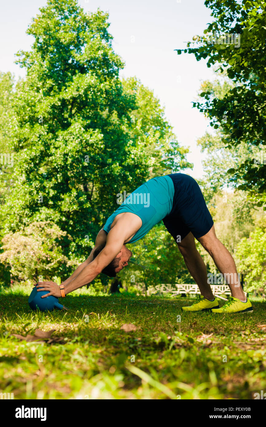 Healthy man doing push up holding kettlebell at the park Stock Photo ...