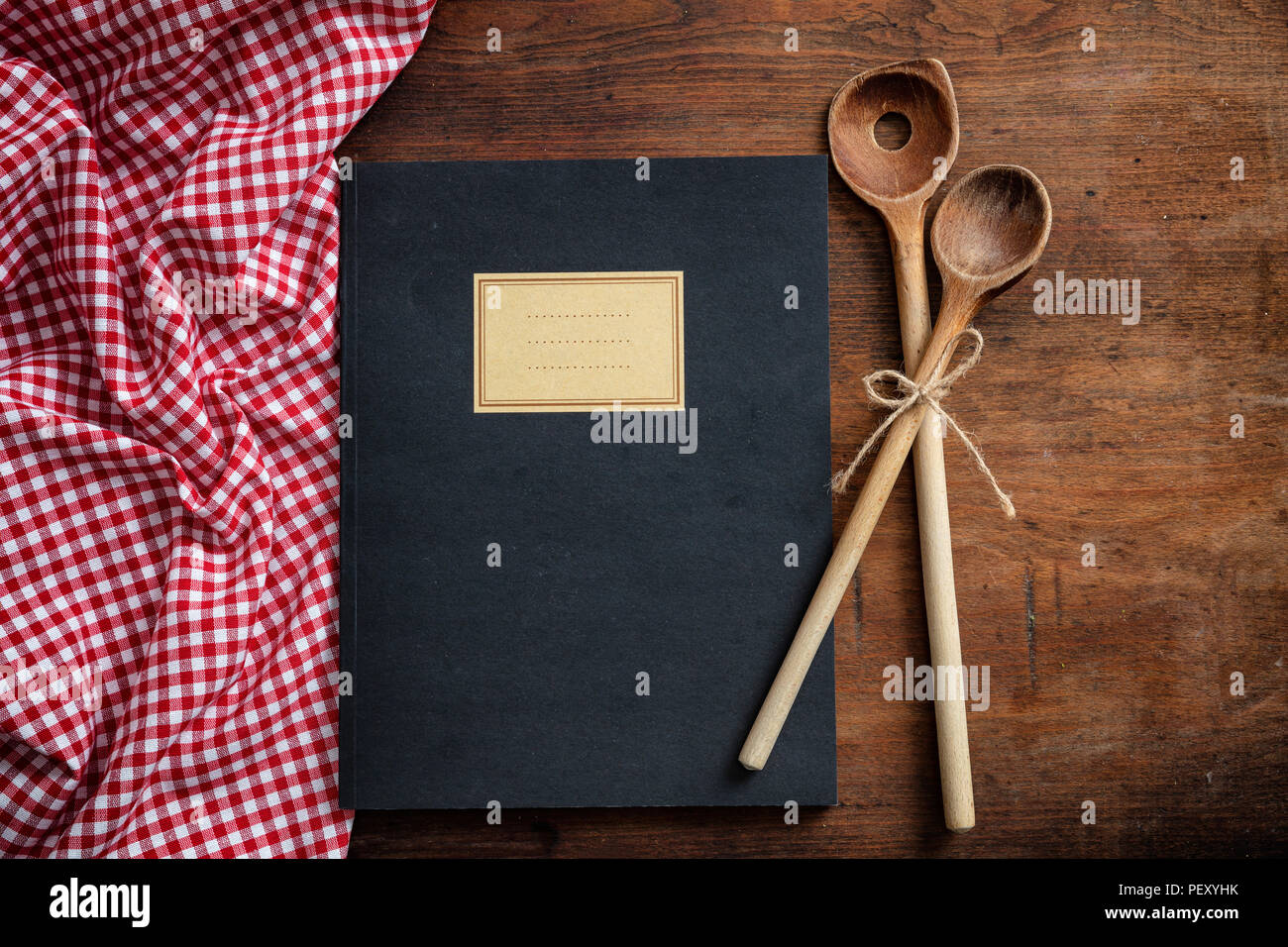 Cooking recipes book. Notebook, kitchen utensils and red tablecloth on wooden table, top view Stock Photo