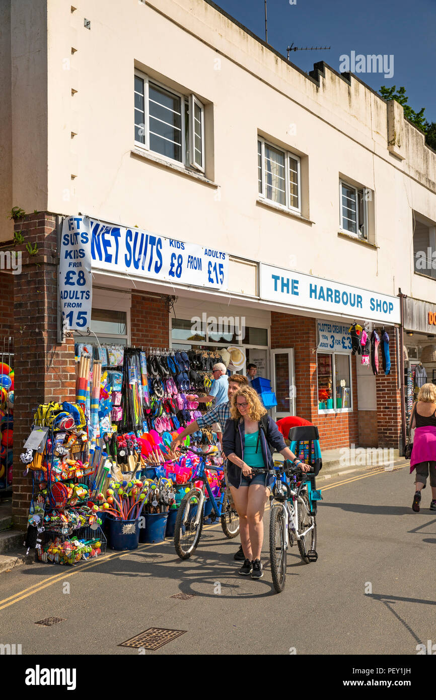 UK, Cornwall, Padstow, North Quay, visitors with bicycles passing colourful beach goods shop Stock Photo