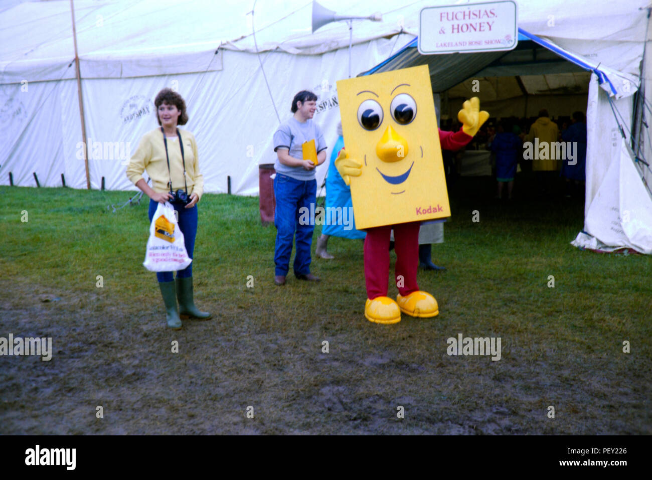 A rainy day at the Lakeland Rose Show, Cumbria with a Kodak mascot. Original image taken from a colour negative in 1985 Stock Photo