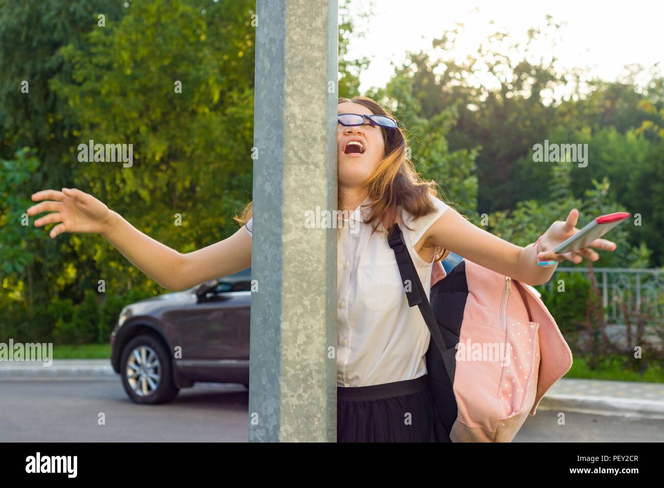 Portrait of young inattentive girl, distracted by mobile phone. Girl crashed into street post, dropped phone Stock Photo