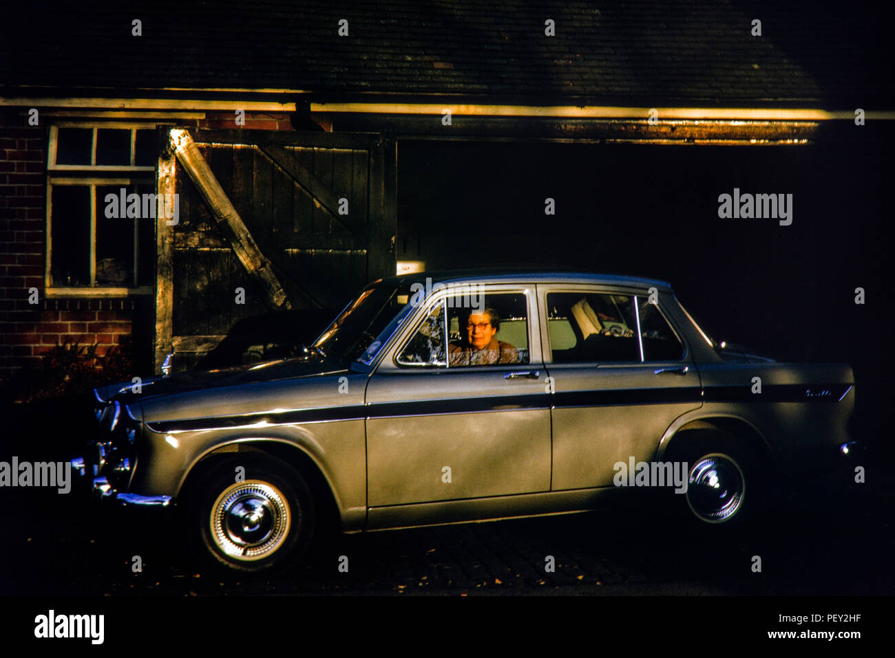 An owner of a new Singer Gazelle VI proudly takes a picture in evening sunlight. The car was new in October 1965 and the registration was JPJ 79C Stock Photo