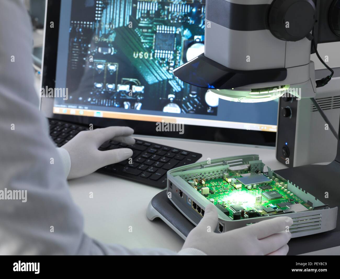 Engineer using a stereo microscope to inspect a printed circuit board