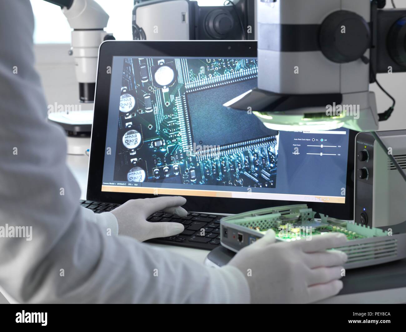 Engineer using a stereo microscope to inspect a printed circuit board