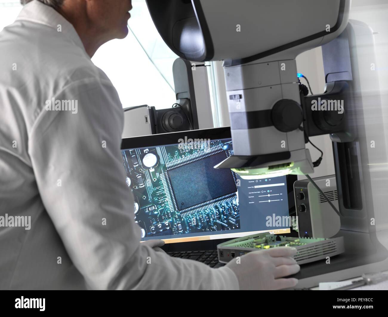 Engineer using a stereo microscope to inspect a printed circuit board