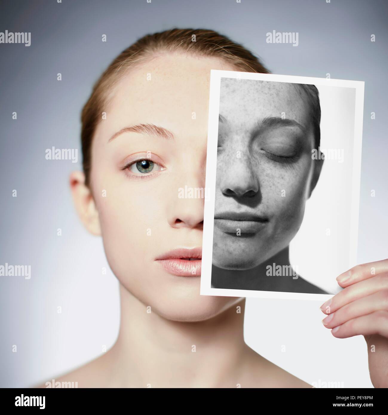 Sun damage. Woman holding a photograph in front of her face showing the damage sun exposure has done to her skin. Stock Photo