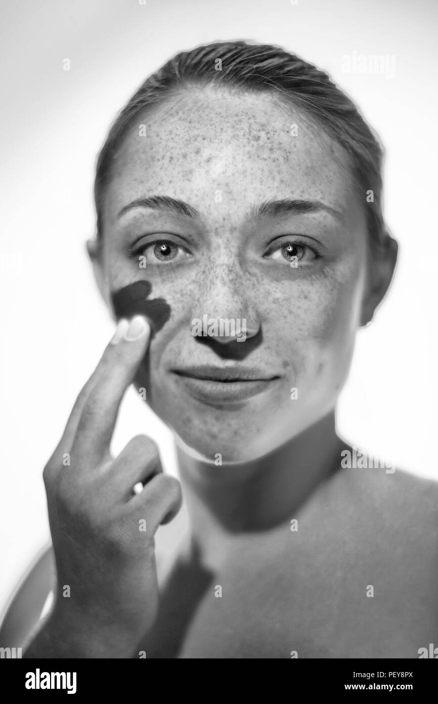 Woman applying sunscreen to her cheek. Stock Photo