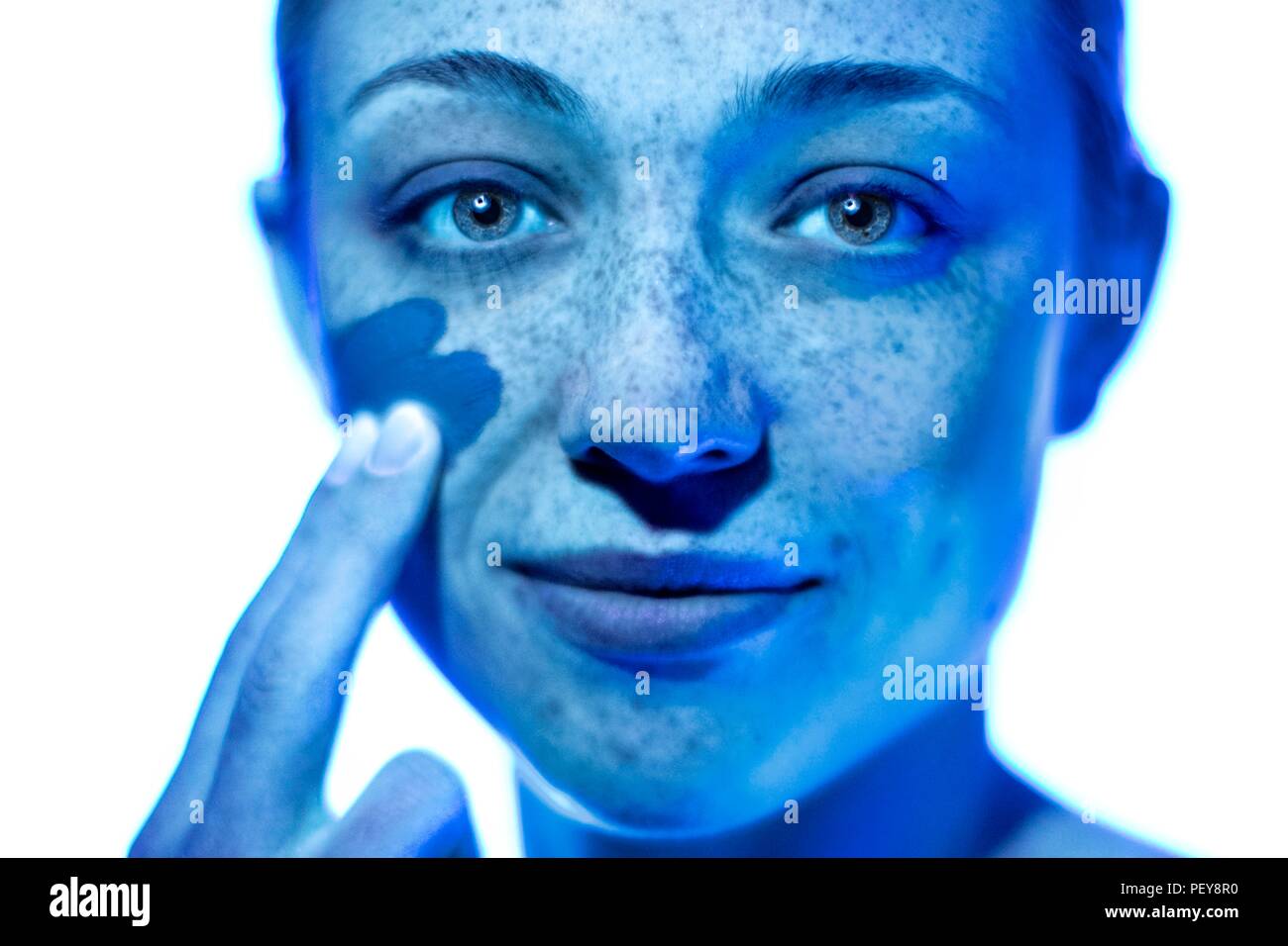 Woman applying sunscreen to her cheek. Stock Photo