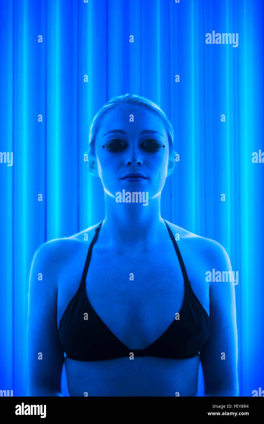Woman wearing protective goggles in tanning booth. Stock Photo