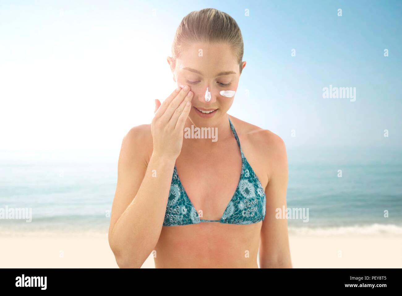 Woman applying sunscreen to her face. Stock Photo