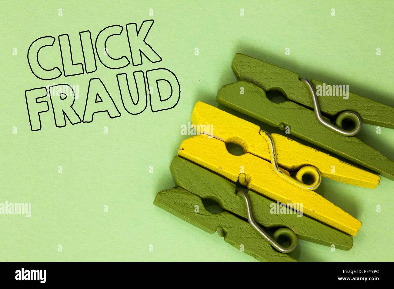 Text sign showing Click Fraud. Conceptual photo practice of repeatedly clicking on advertisement hosted website Three green yellow vintage clothespins Stock Photo