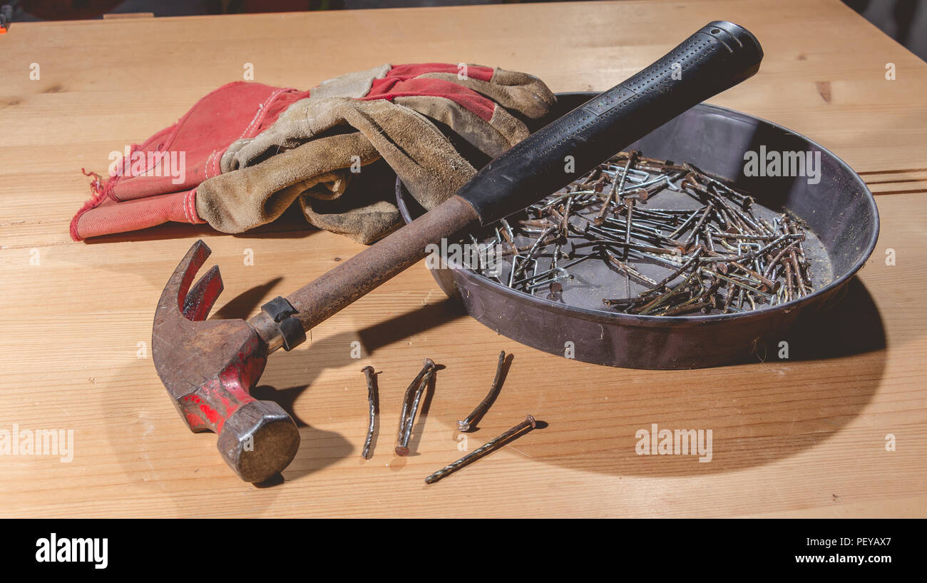 old rusty hammer and construction gloves laid on wooden board in studio Stock Photo