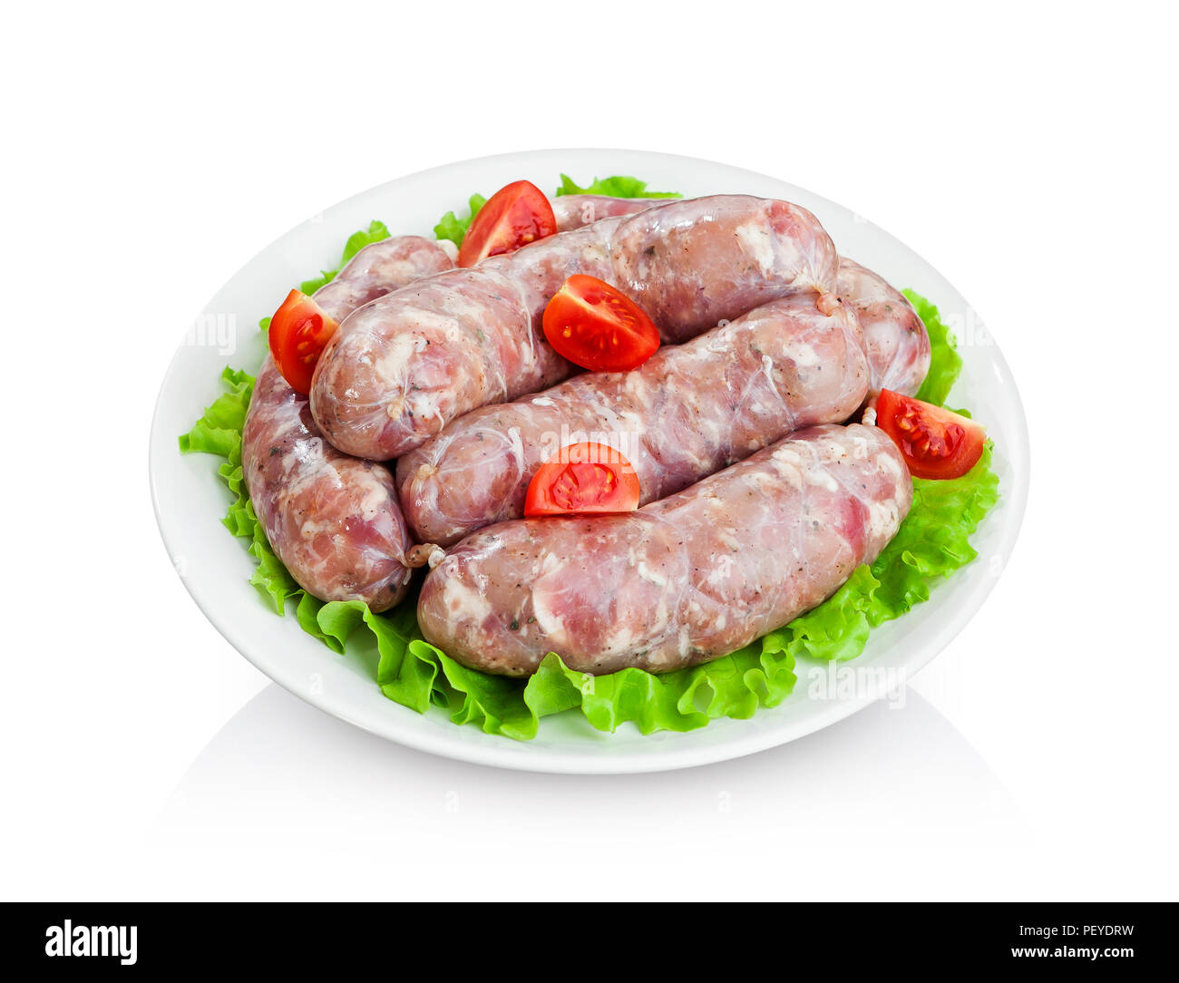 Sausages raw for grilling on plate with lettuce and cherry tomatoes isolated on white background Stock Photo