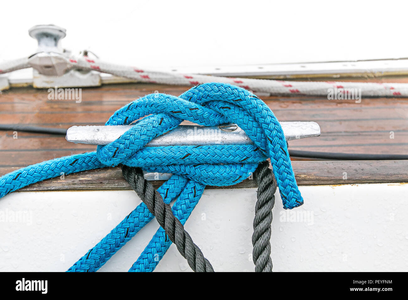 Blue line is wound around a yacht cleat and tied in a knot. Stock Photo