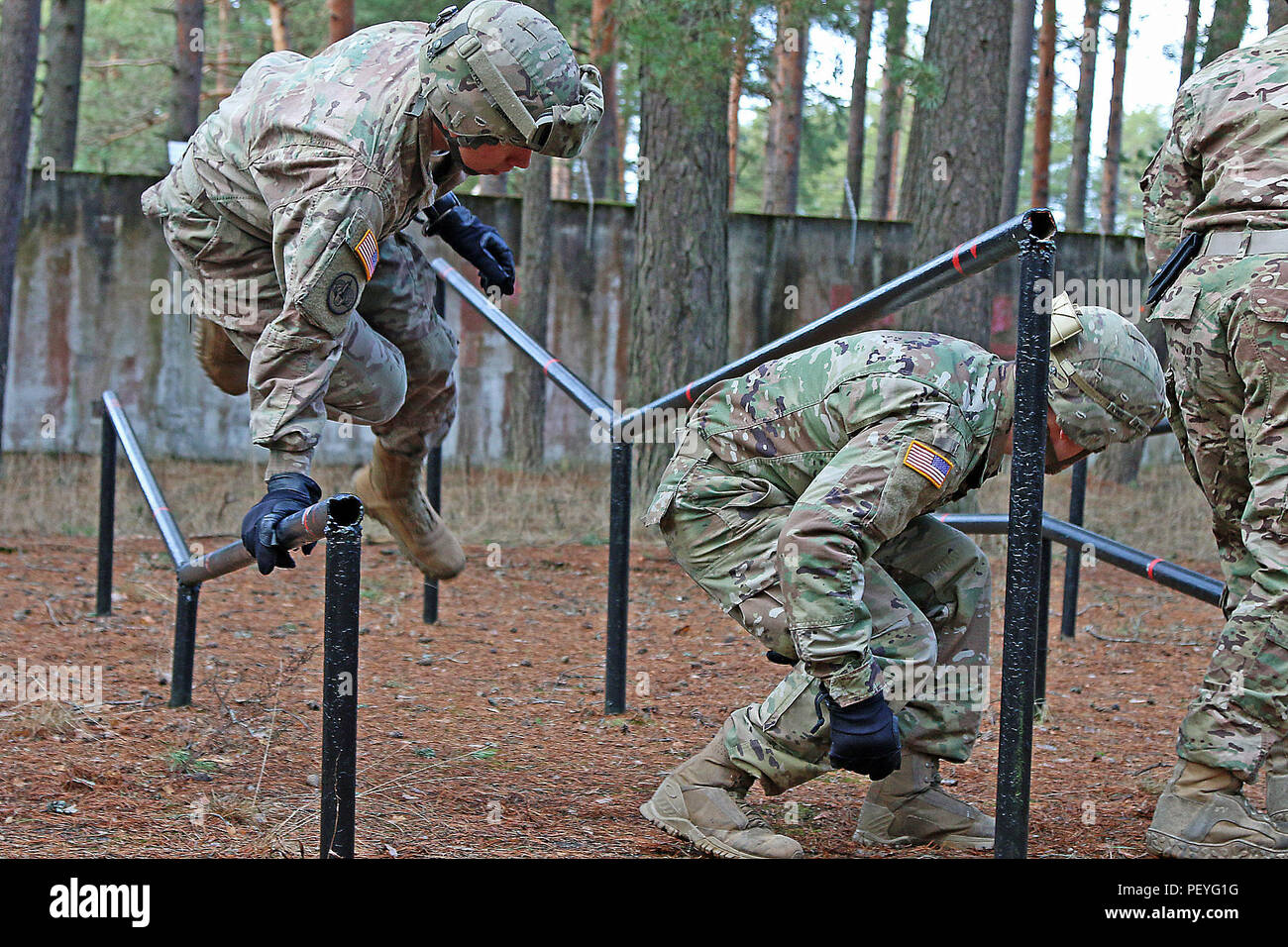 Sgt. Glen Giannello (left), an infantryman assigned to Headquarters and Headquarters Troop, 3rd Squadron, 2nd Cavalry Regiment, navigates an obstacle while warming up for multinational fast rope familiarization training, Feb. 16, at Adazi Military Base, Latvia. Soldiers ran through a short obstacle course before going down the tower, preparing their bodies for necessary movements used during fast rope operations. Latvian partners participated in the training alongside American allies in preparation for an upcoming fast rope operation in support of Operation Atlantic Resolve, a multinational de Stock Photo