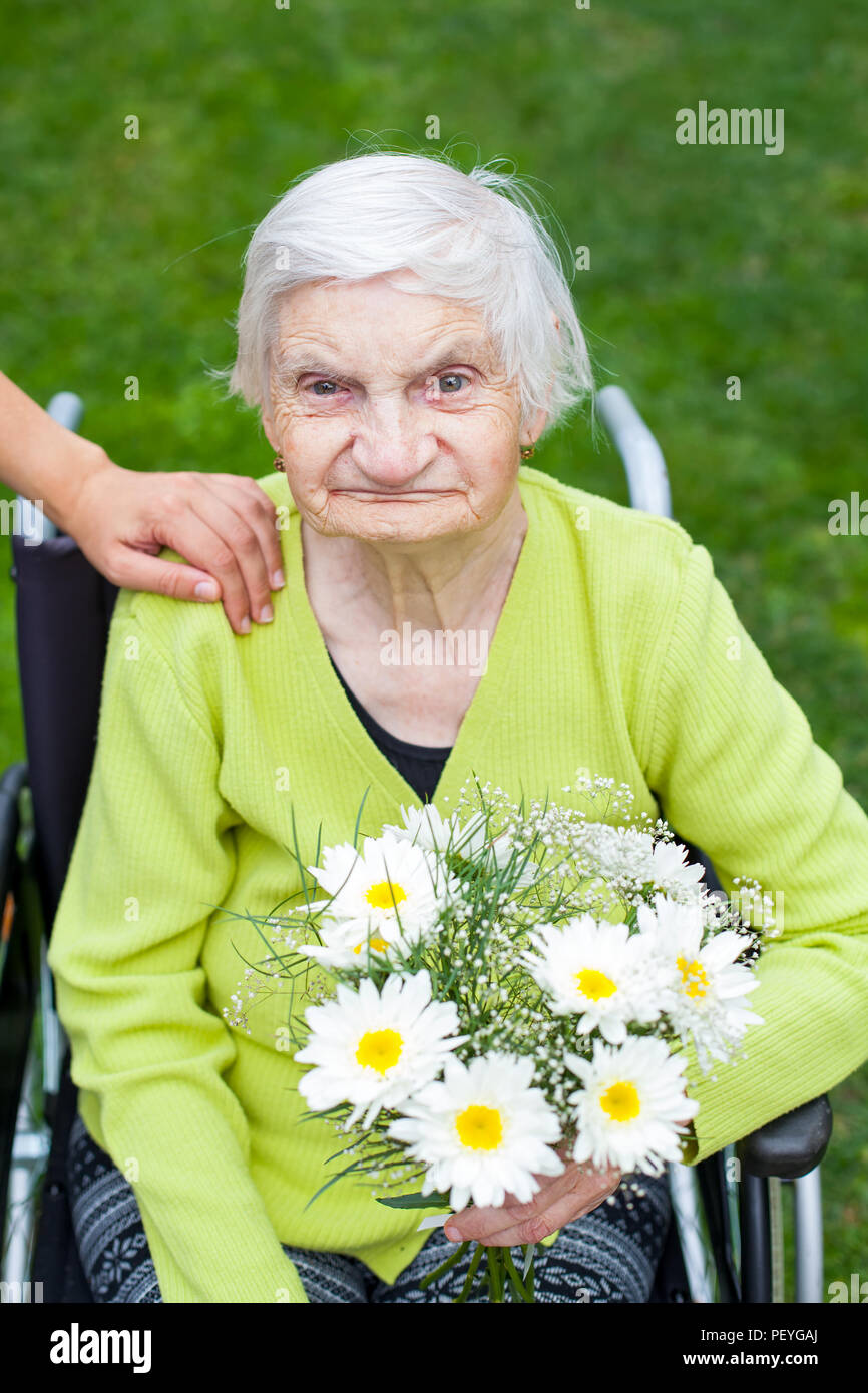 Elderly woman suffering from dementia disease receiving flowers for her