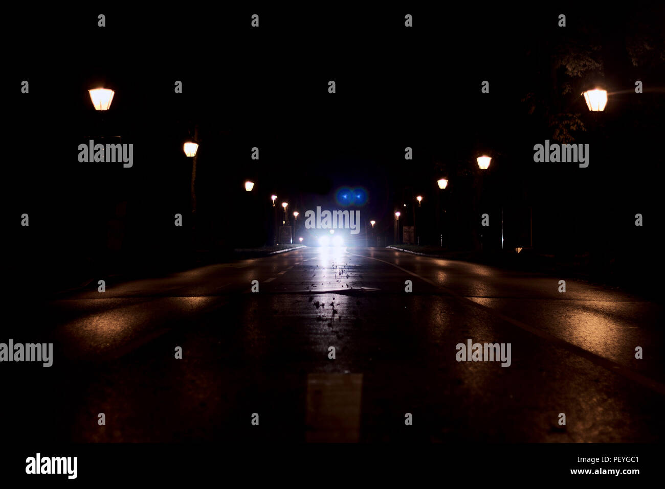 Bright headlights on road reflecting from the asphalt at night Stock Photo
