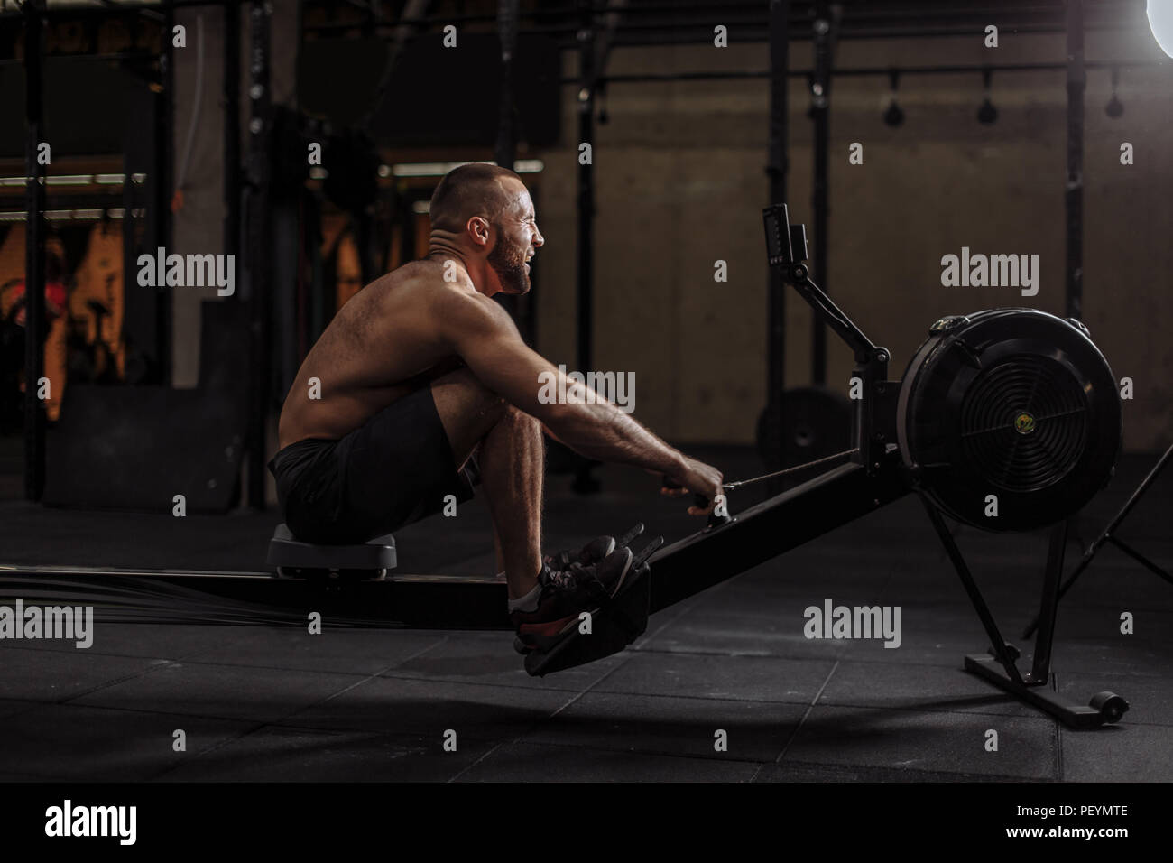 ambitious sportsman is training on the indoor rower with all his might.willpower concept.professional sport Stock Photo