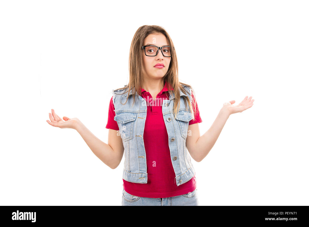Young woman in glasses shrugging with shoulders looking clueless at camera isolated on white background Stock Photo