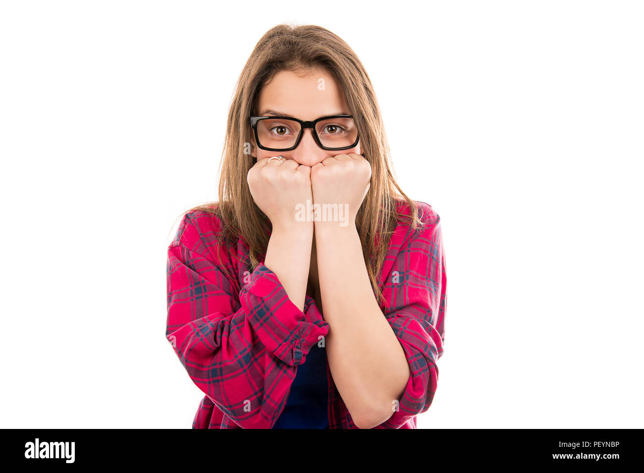 Young woman in glasses and plaid shirt covering mouth in fear and panic looking at camera isolated on white background Stock Photo