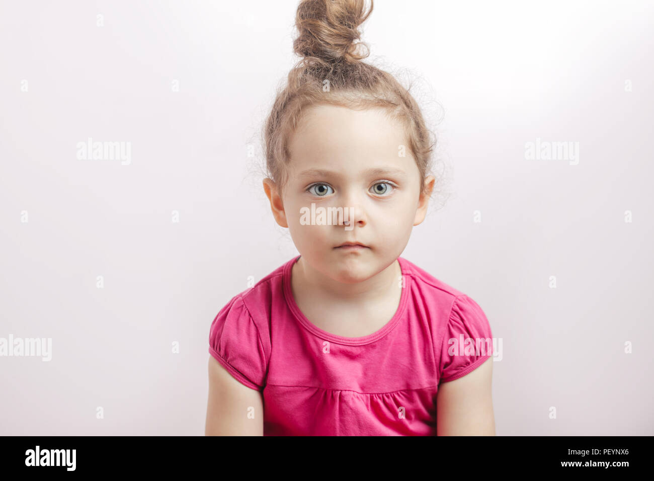 Adorable Cute Girl With Hair Bun And Serious Face Looking At The