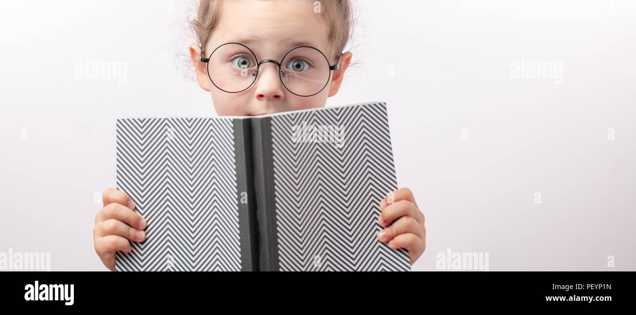 fearful girl is covering her face with a book. waful stories for children. copy space. fear