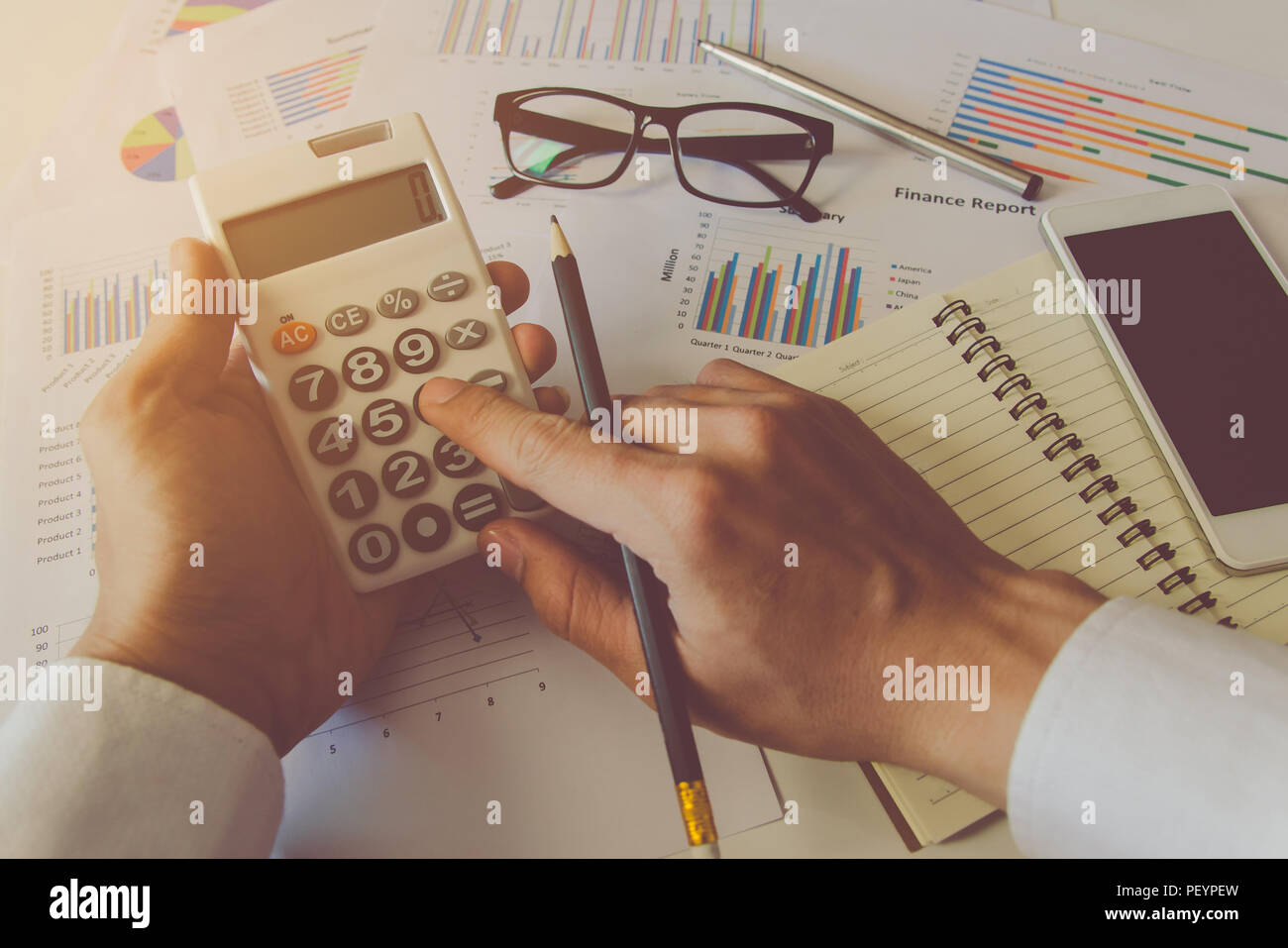 Man hand using a financial calculator and Financial data analyzing on desk at home Stock Photo