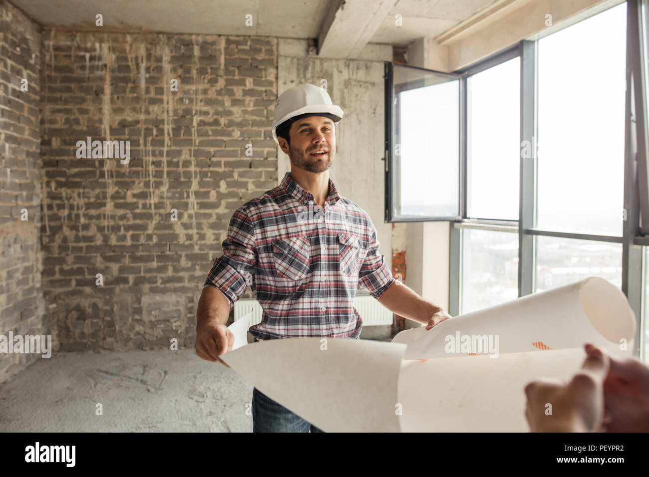 attractive cheerful builder has got the blueprint at work place. close up portrait Stock Photo
