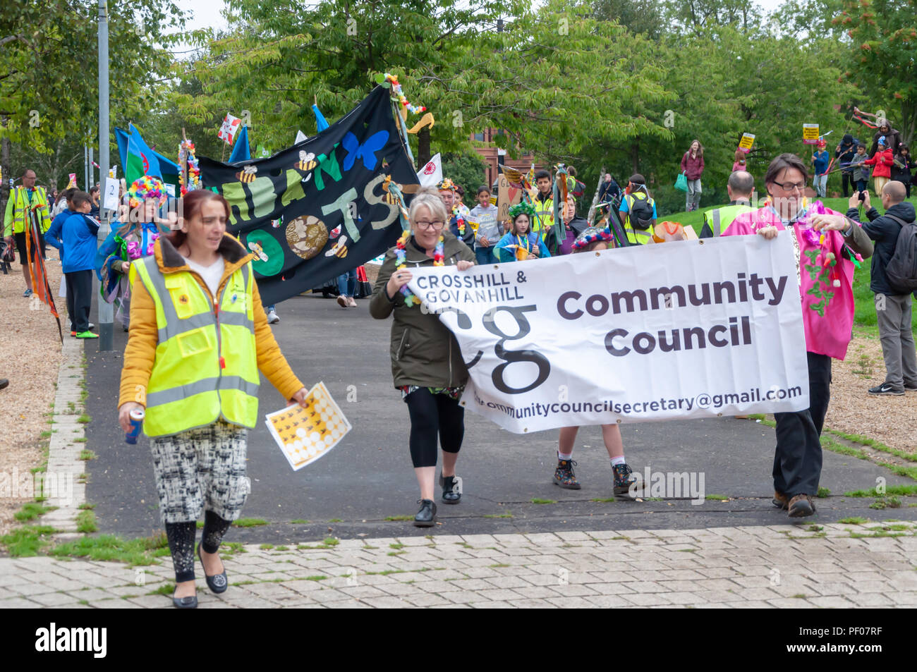 Glasgow, Scotland, UK. 18th August, 2018. A banner saying Crosshill & Govanhill  Community Council is carried at the start of the parade of the Govanhill International Festival & Carnival. This year's parade includes community groups, a pipe band, drummers, dancers, jugglers, roller skaters and a brass band all starting at Govanhill Park and travelling through the streets of Govanhill finishing at the Queen's Park Arena. Credit: Skully/Alamy Live News Stock Photo