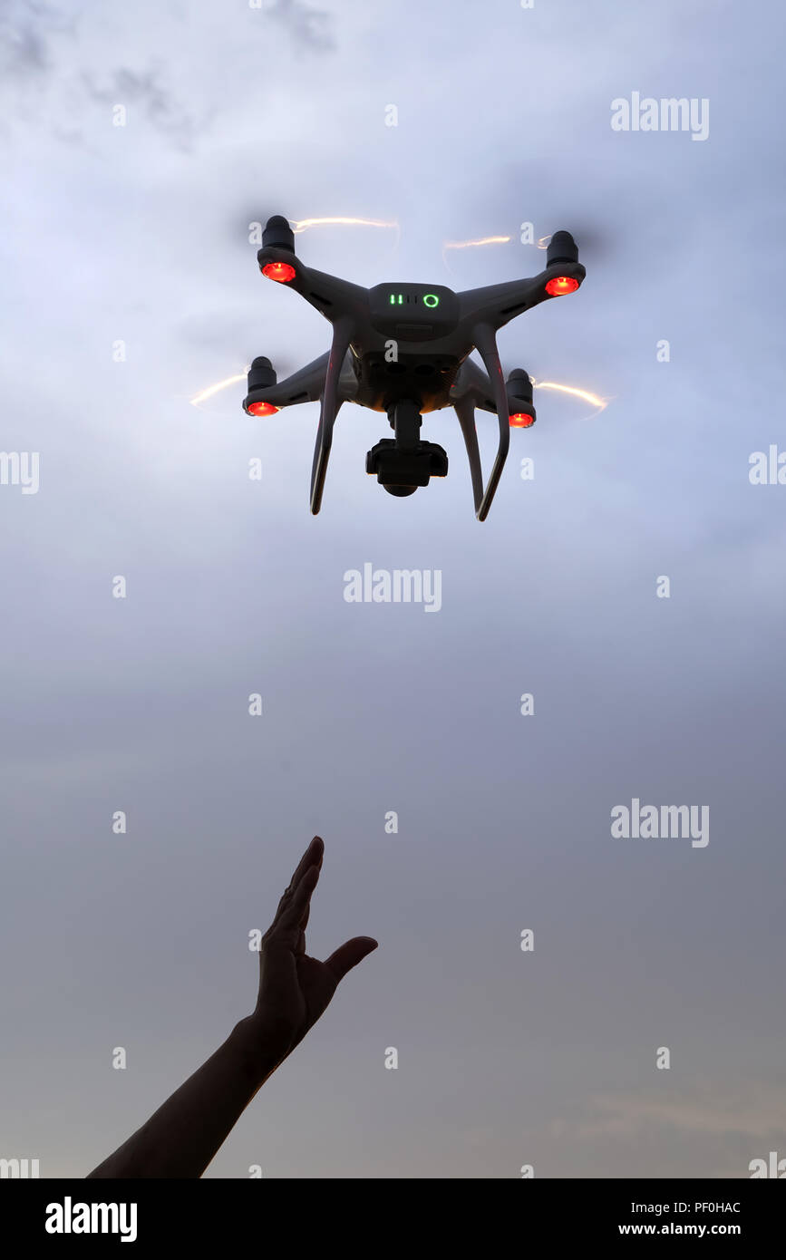 Hand catching drone aircraft in sunset sky background, camera operator of aerial photography