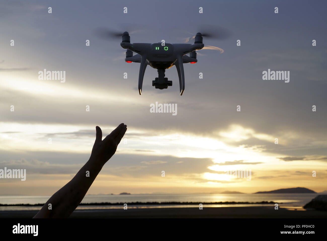 Hand catching drone aircraft in sunset sky background, camera operator of aerial photography