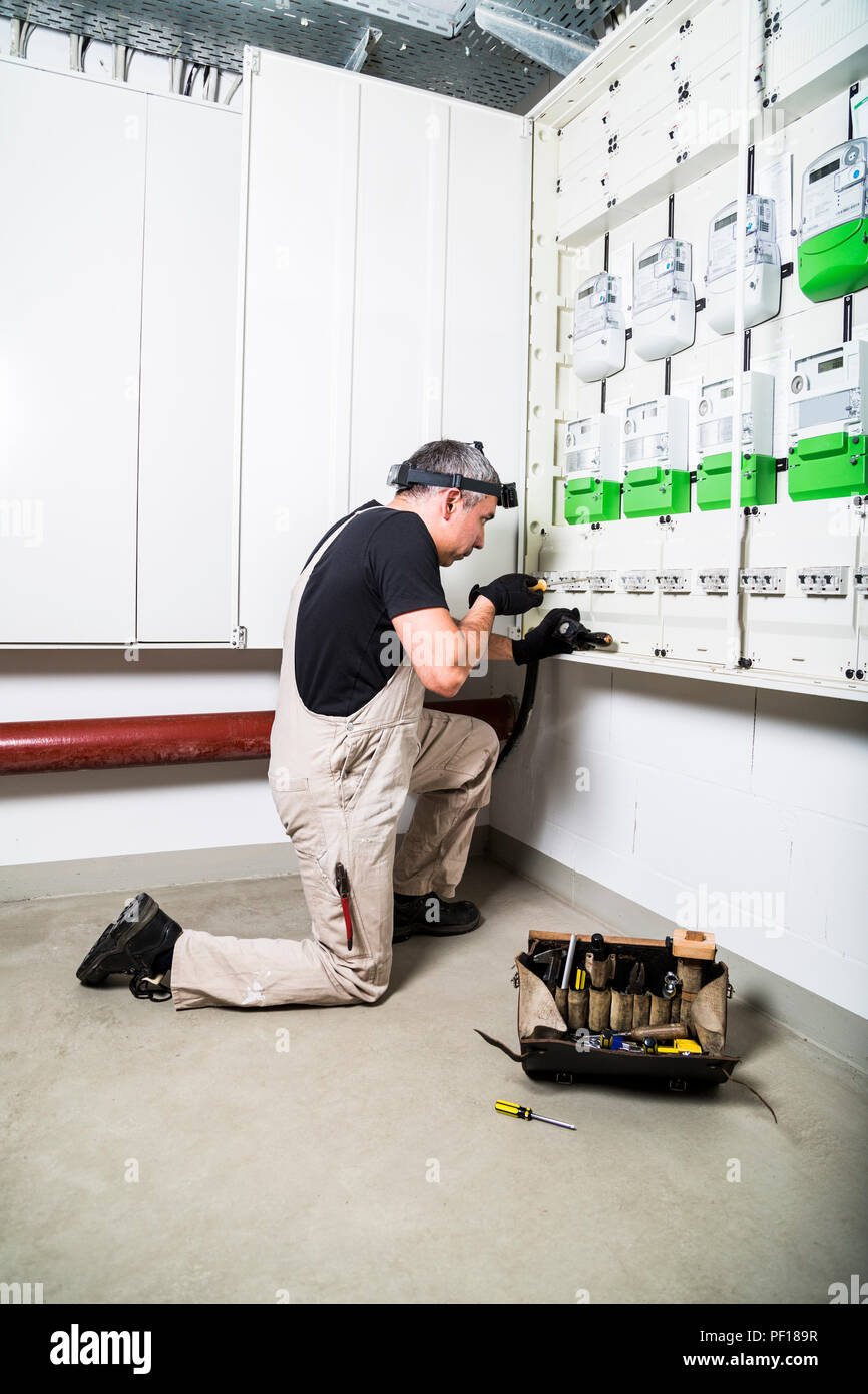 Electrician with box of tools fixing fuse box or switch box