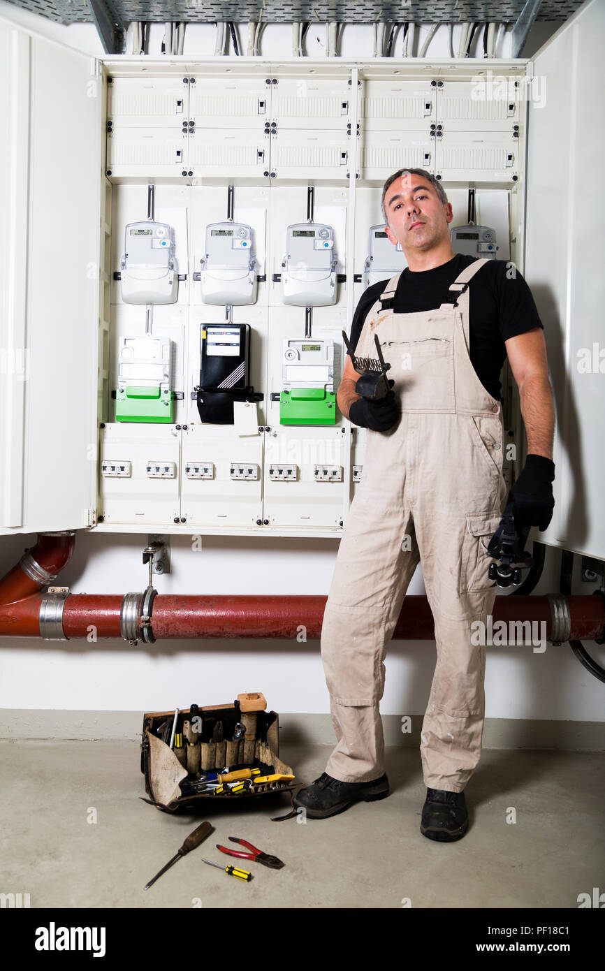 Electrician with box of tools standing near distribution board Stock Photo