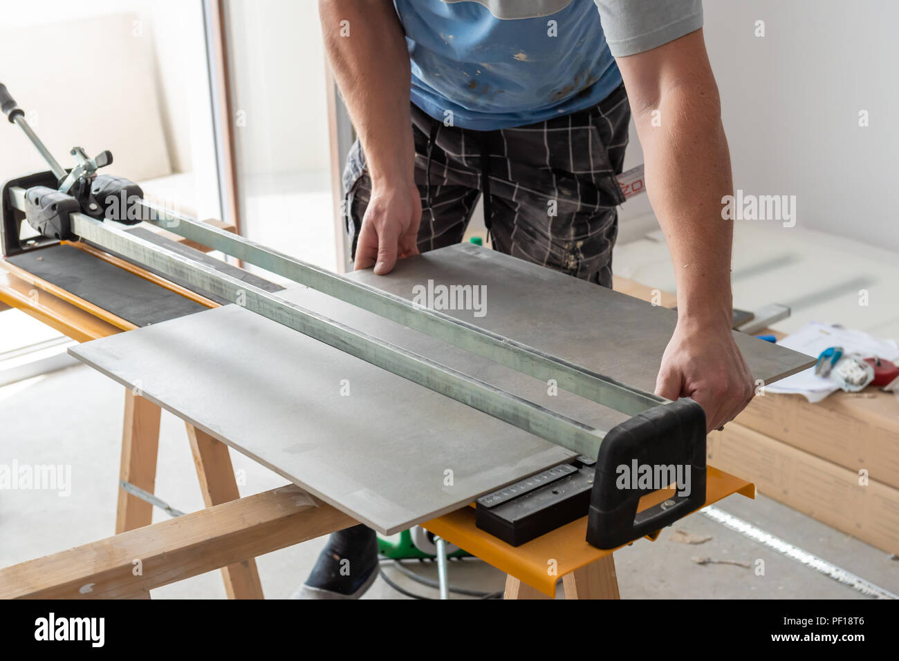 The Man Is Cutting The Floor Tiles Using A Tile Cutter Machine