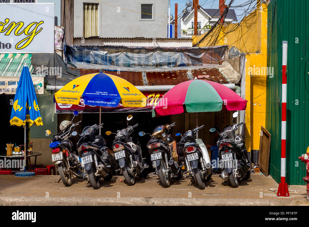 Motorcycles parked in front of a cafe under colorful umbrellas in Dalat Stock Photo