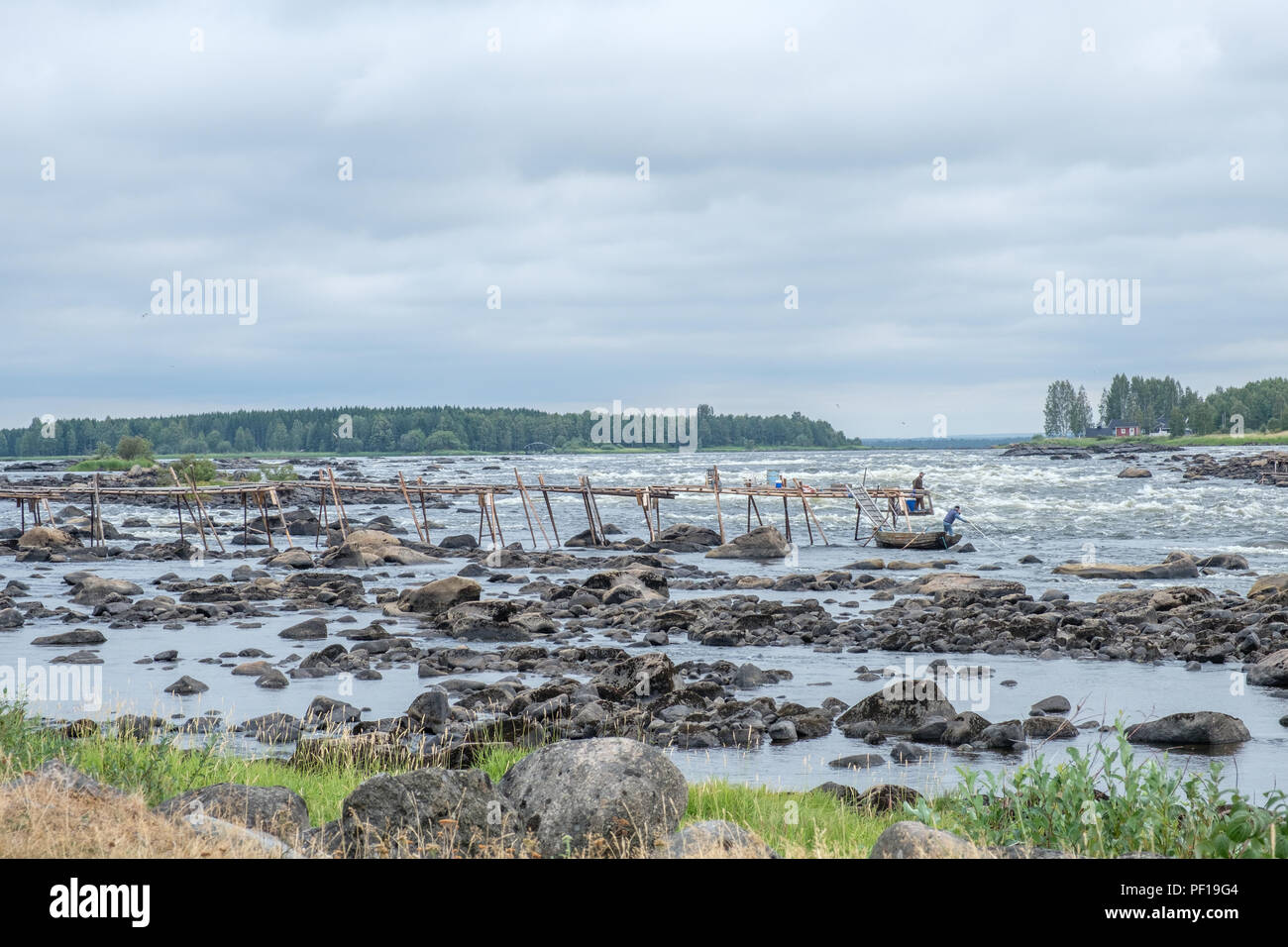 Unrecognizable people fish at Kukkola rapids on the Swedish side of the border between Sweden and Finland. Stock Photo