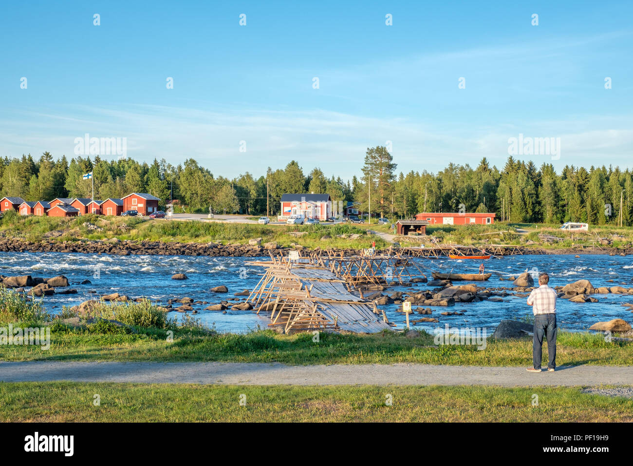 Tourist enjoys the view from Kukkola in Sweden across Torne river towards Finland. Kukkola rapids has been a fishing site since medieval times Stock Photo