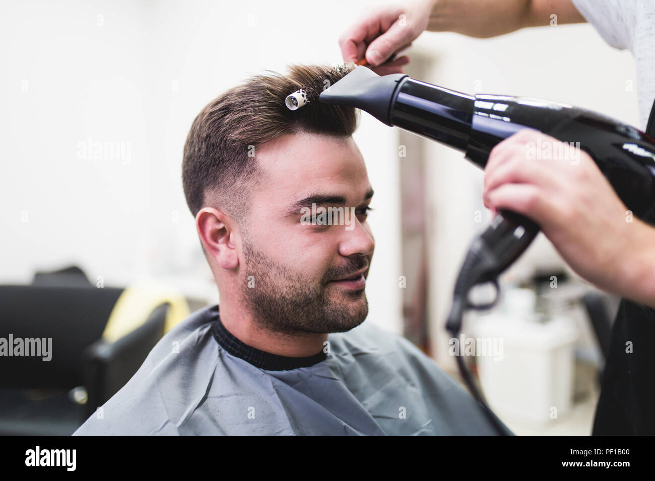 Hairdresser blow drying his client s hair Stock Photo Alamy