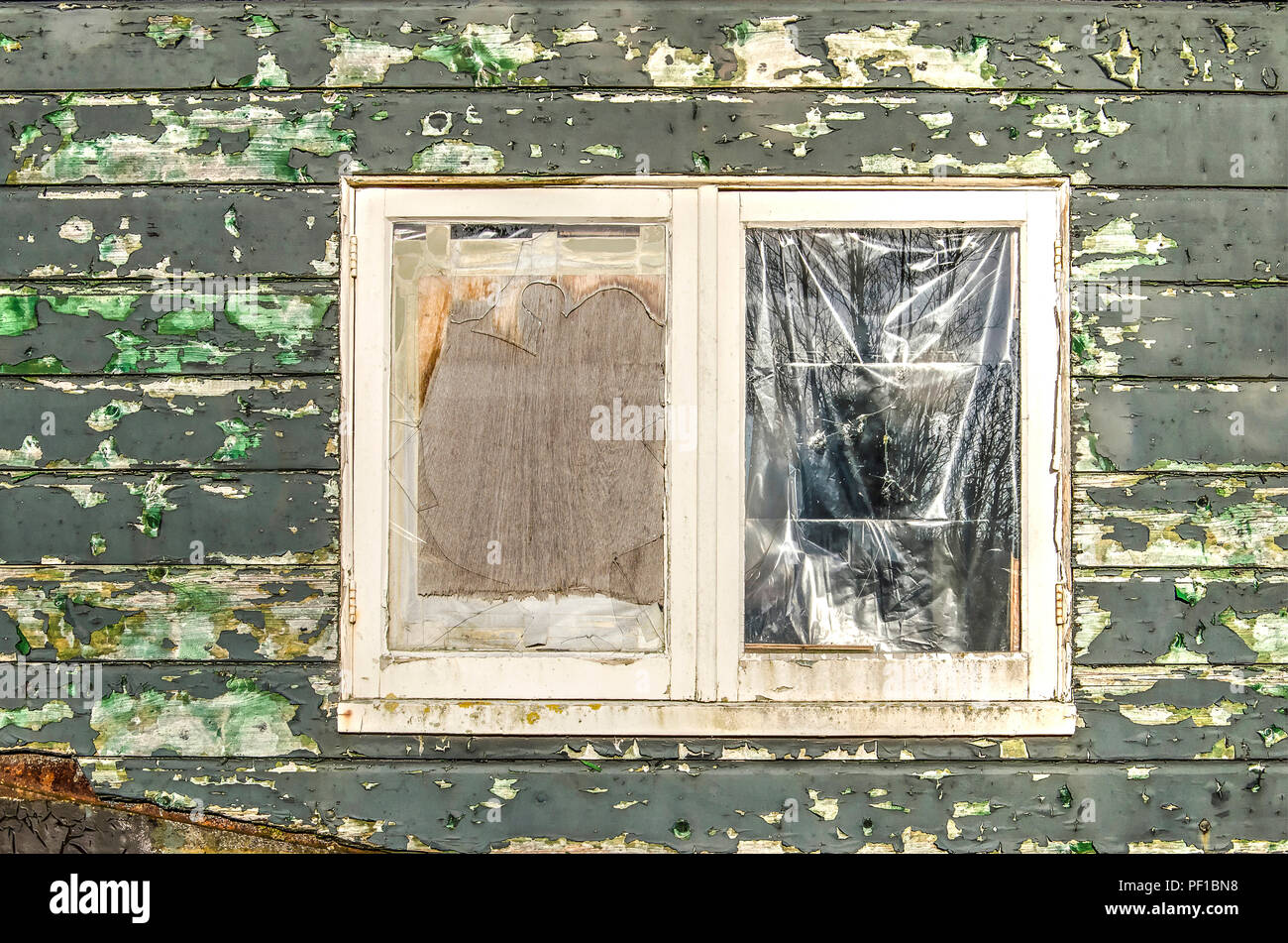 Window with broken glass, closed with plastic and plywood; in a wooden