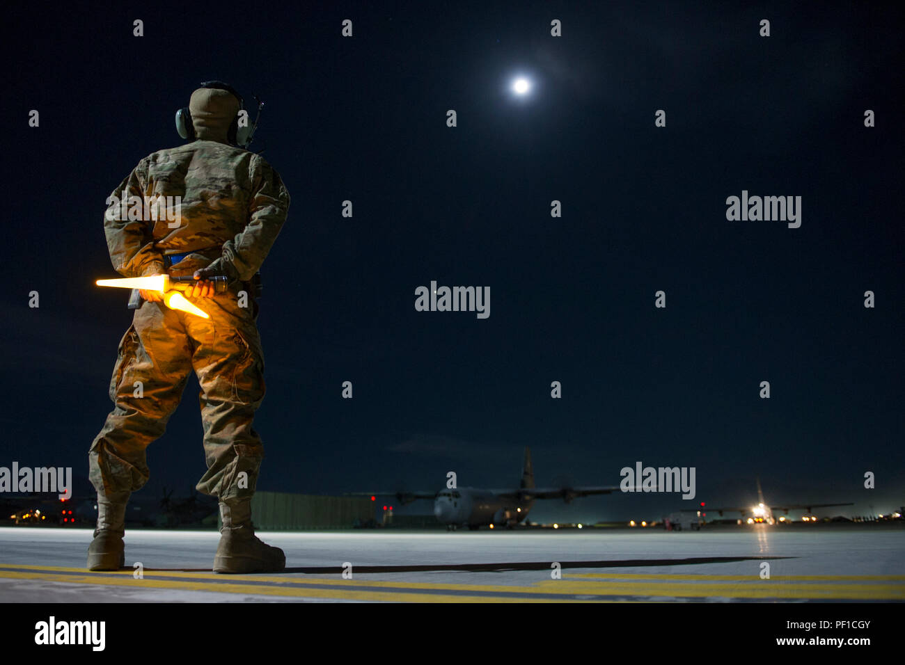 Senior Airman Alec Flores, 455th Expeditionary Aircraft Maintenance Squadron crew chief, prepares to guide a C-130J Super Hercules on to a taxiway as it leaves on a night sortie at Bagram Air Field, Afghanistan, Feb. 22, 2016. The 455th EAMXS ensures that aircraft at Bagram are prepared for flight and return them to a mission-ready state once they land. (U.S. Air Force photo/Tech. Sgt. Robert Cloys) Stock Photo