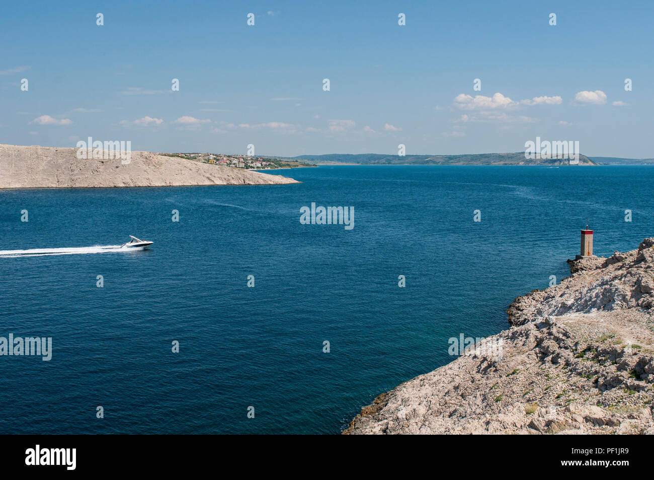 Croatia: a speedboat and the little red lighthouse on the cliff in front of Paški Most, the 1968 bridge that connects the main land and the Pag island Stock Photo