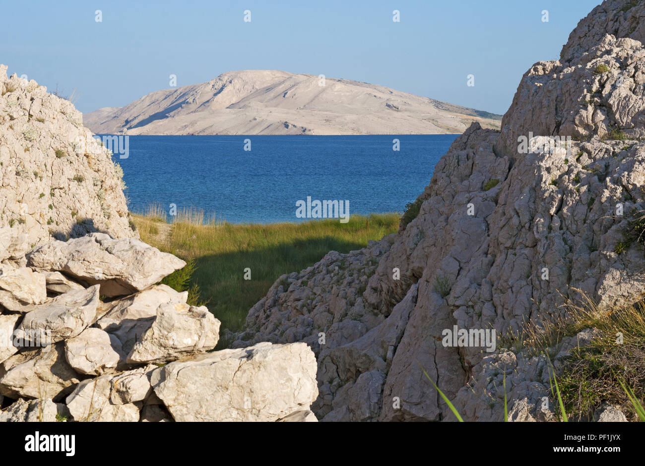Croatia, Europe: a glimpse of Rucica, the pebbled beach nestled in a barren bay with little green plants and desert landscape on the famous Pag island Stock Photo