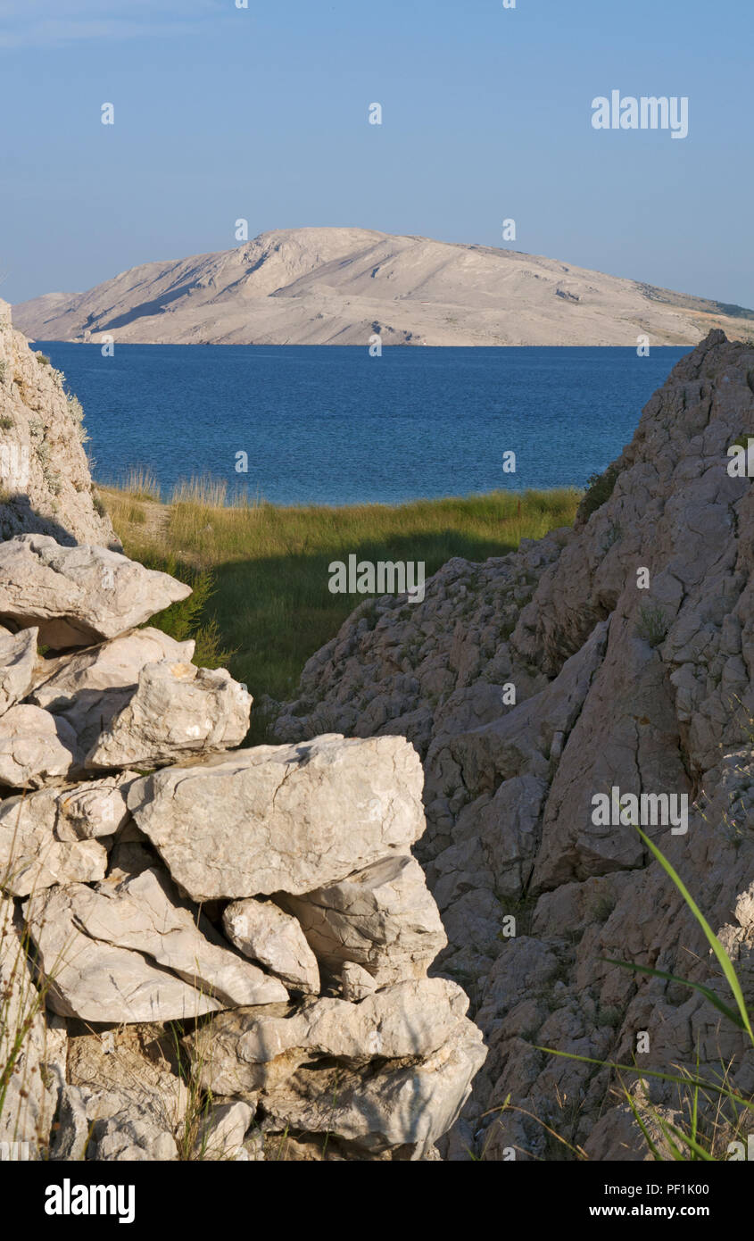 Croatia, Europe: a glimpse of Rucica, the pebbled beach nestled in a barren bay with little green plants and desert landscape on the famous Pag island Stock Photo