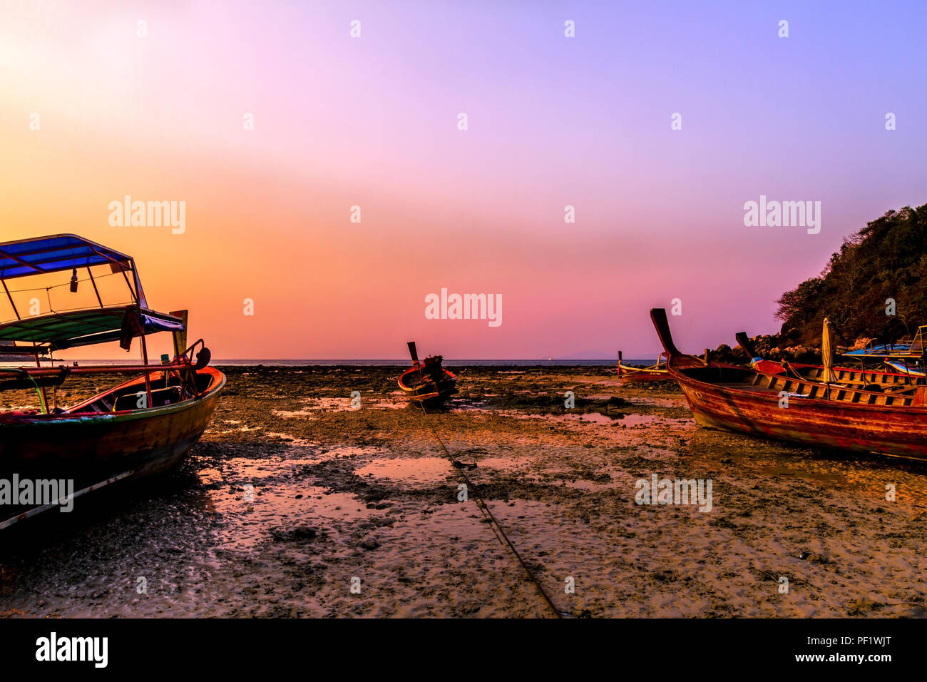 Raya Island during sunset and low tide as the waters receed and strand the boats until the waters rise again in Thailand. Stock Photo