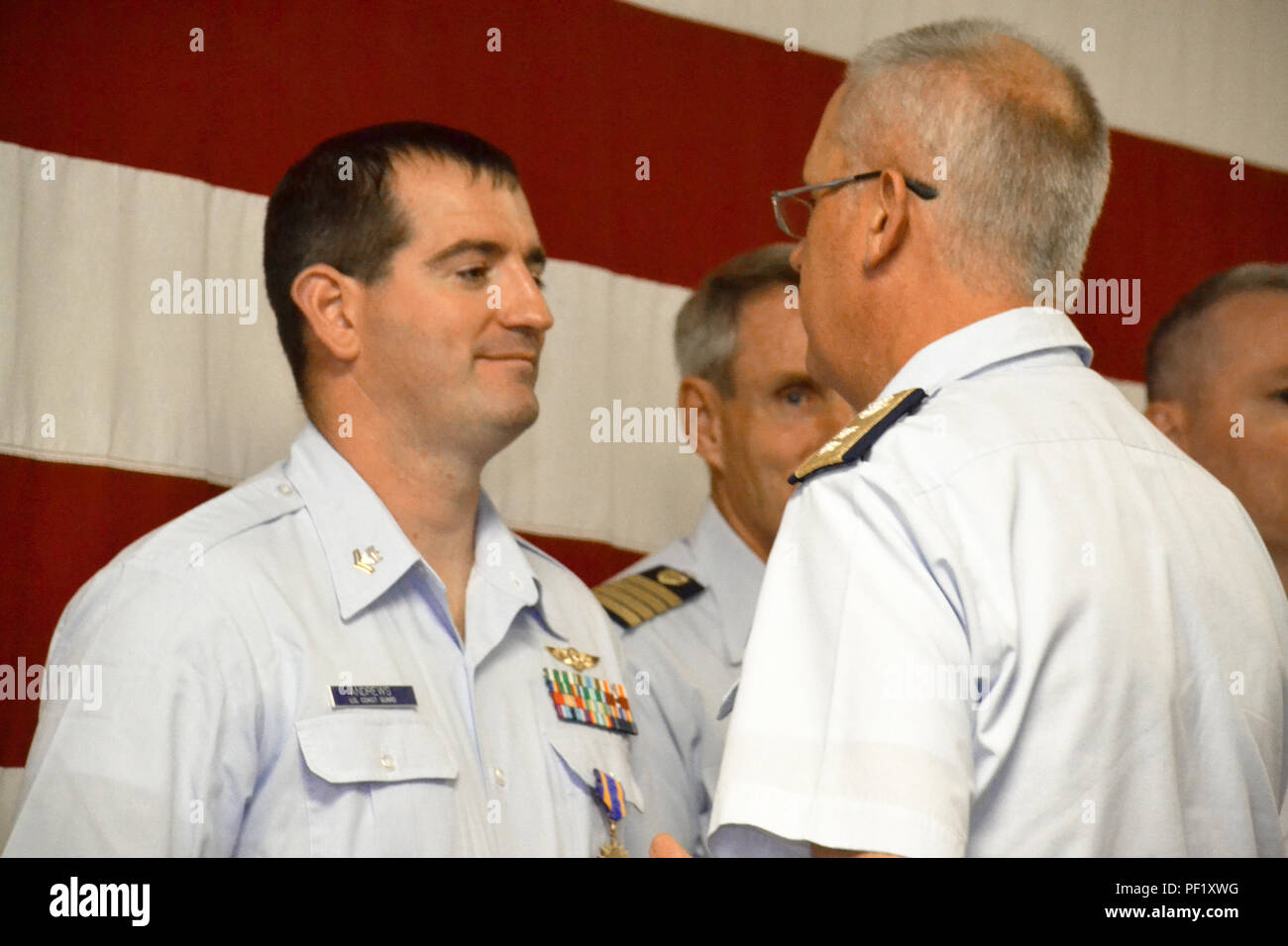 Rear Adm. Scott Buschman, commander Coast Guard Seventh District, Miami, presents an Air Medal to Petty Officer 2nd Class Joshua Andrews, a flight mechanic at Air Station Clearwater, Fla., during an awards ceremony at the station Feb. 24, 2016. Andrews was commended for his performance in saving 12 lives during Hurricane Joaquin. (U.S. Coast Guard photo by Auxiliarist Joe Perez) Stock Photo