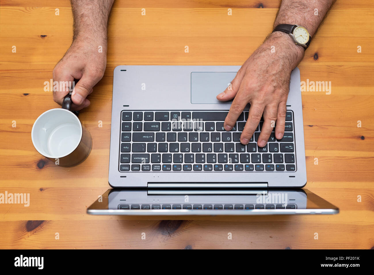 Man working with laptop. Empty cup, cofee break time. Top view. Stock Photo
