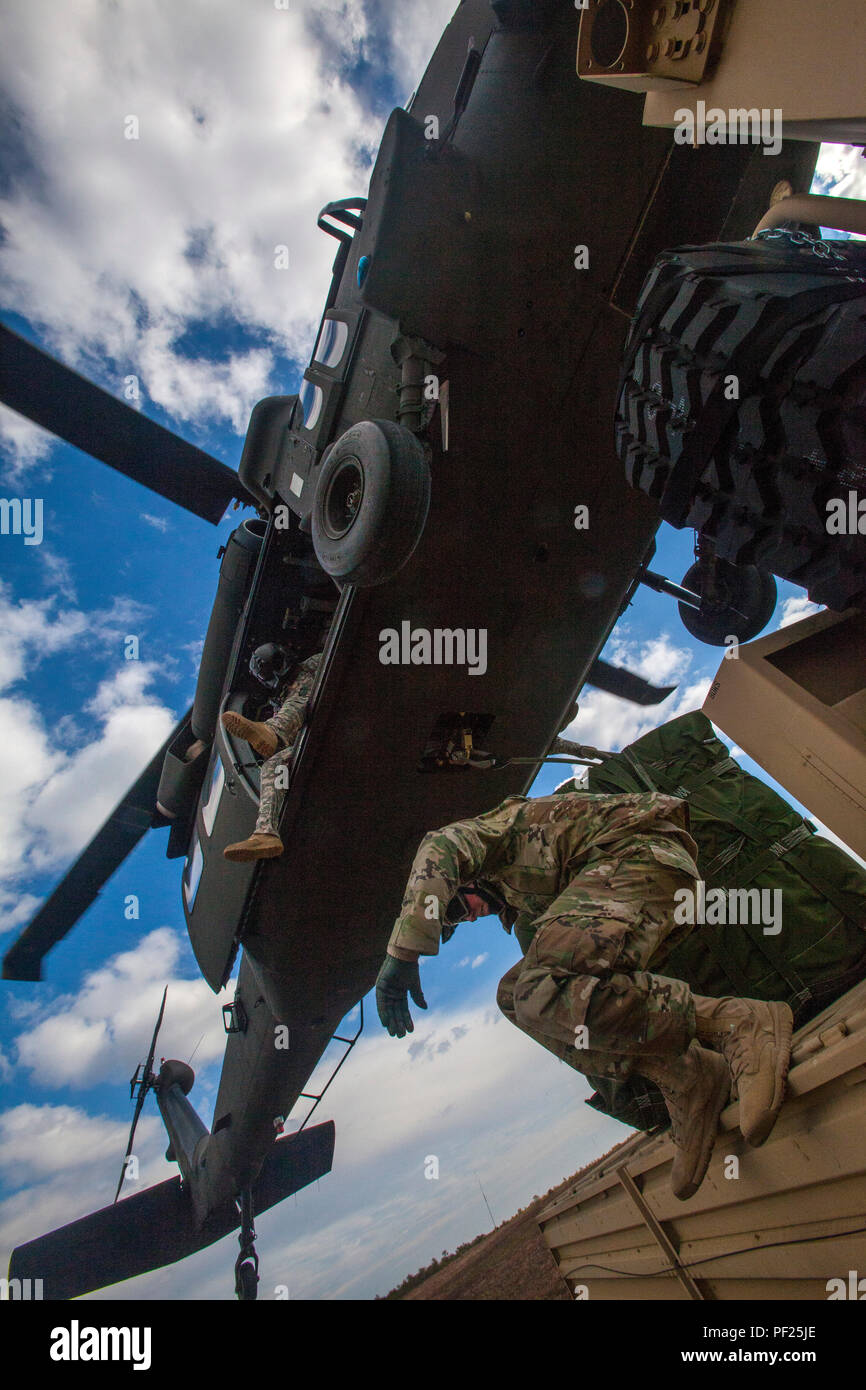 Soldiers from the 404th Civil Affairs Battalion (Airborne), United States Army Reserve, run from their vehicle after successfully sling loading cargo onto a 1-150th Assault Helicopter Battalion, New Jersey Army National Guard, Black Hawk helicopter during joint training at Coyle Drop Zone, Joint Base McGuire-Dix-Lakehurst, N.J., Feb. 29, 2016. (U.S. Air National Guard photo by Master Sgt. Mark C. Olsen/Released) Stock Photo