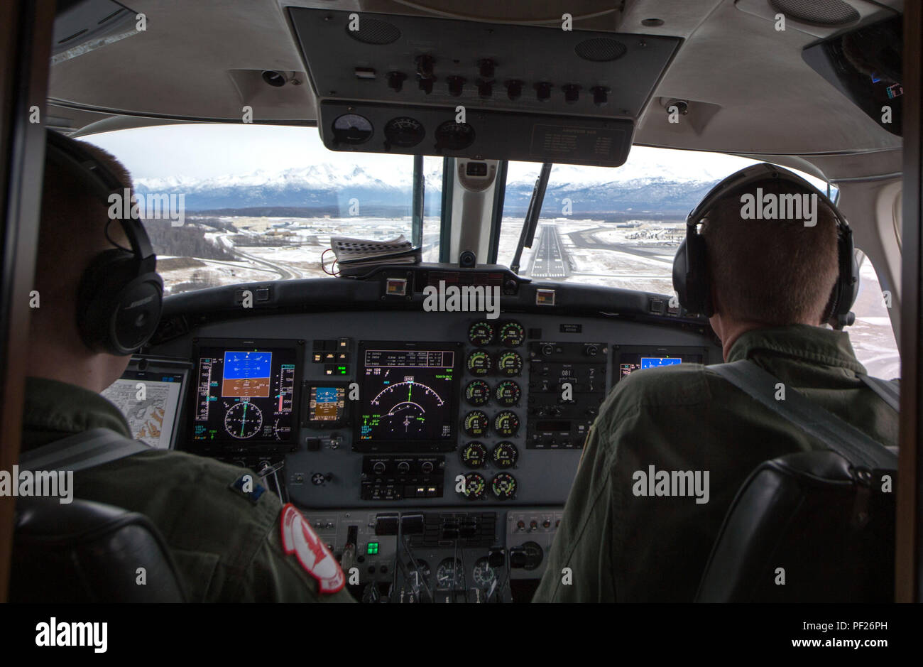 Air Force Maj. Ryan Wong, left, prepares to land at Joint Base Elmendorf-Richardson, Alaska, Feb. 23, 2016, while Lt. Col. Blake Johnson watches as part of a site pilot training. Wong and Johnson are both assigned to the 517th Airlift Squadron. (U.S. Air Force photo by Staff Sgt. Sheila deVera) Stock Photo