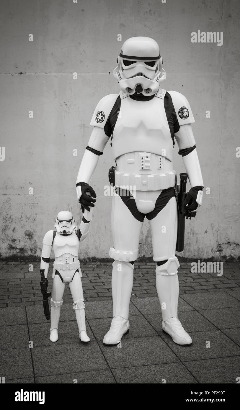 A male cosplayer dressed as a Stormtrooper from the Star Wars franchise and holding the hand of his Stormtrooper son in a comic con family portrait Stock Photo